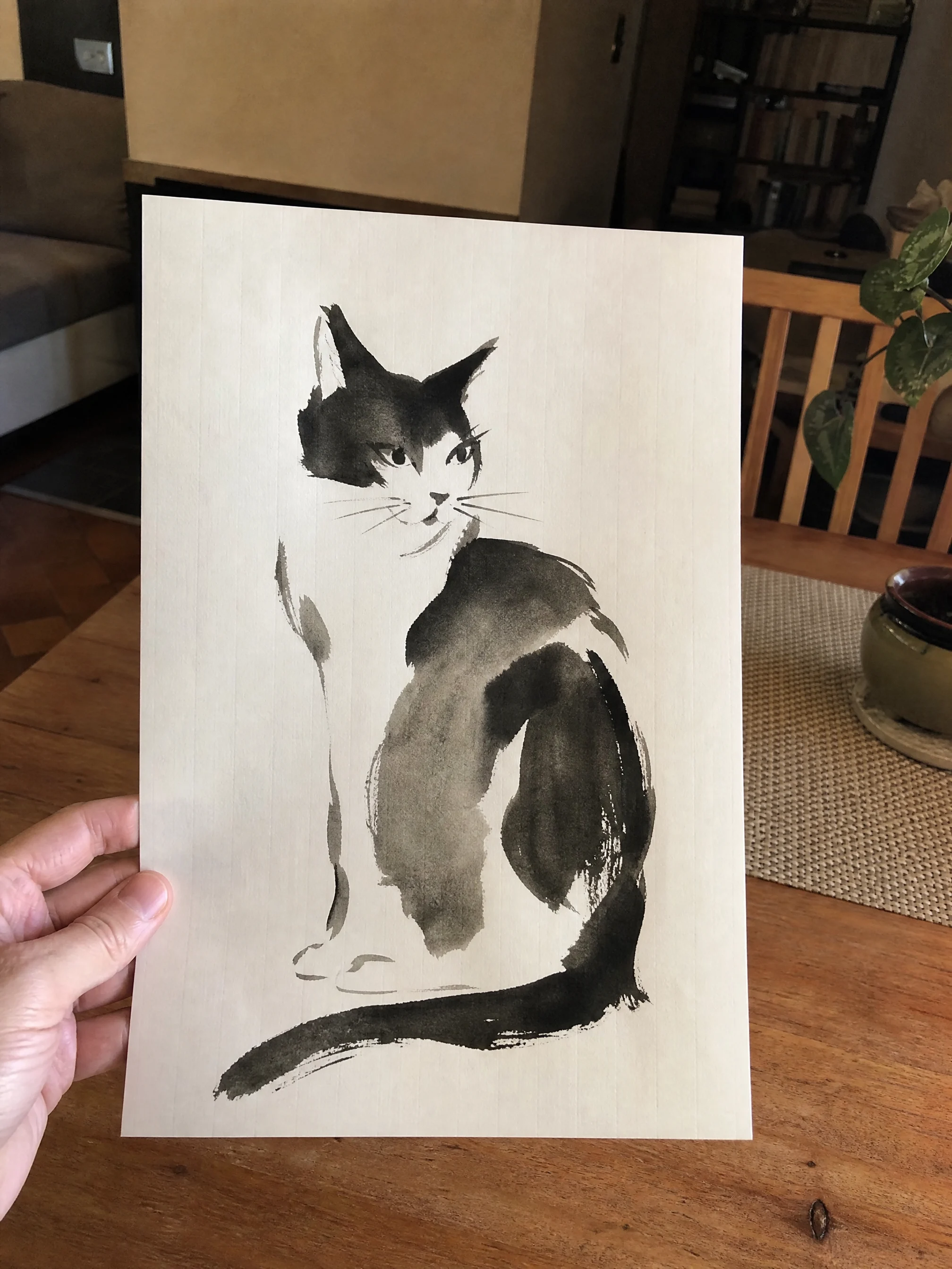 A finished sumi-e ink cat painting held in hand